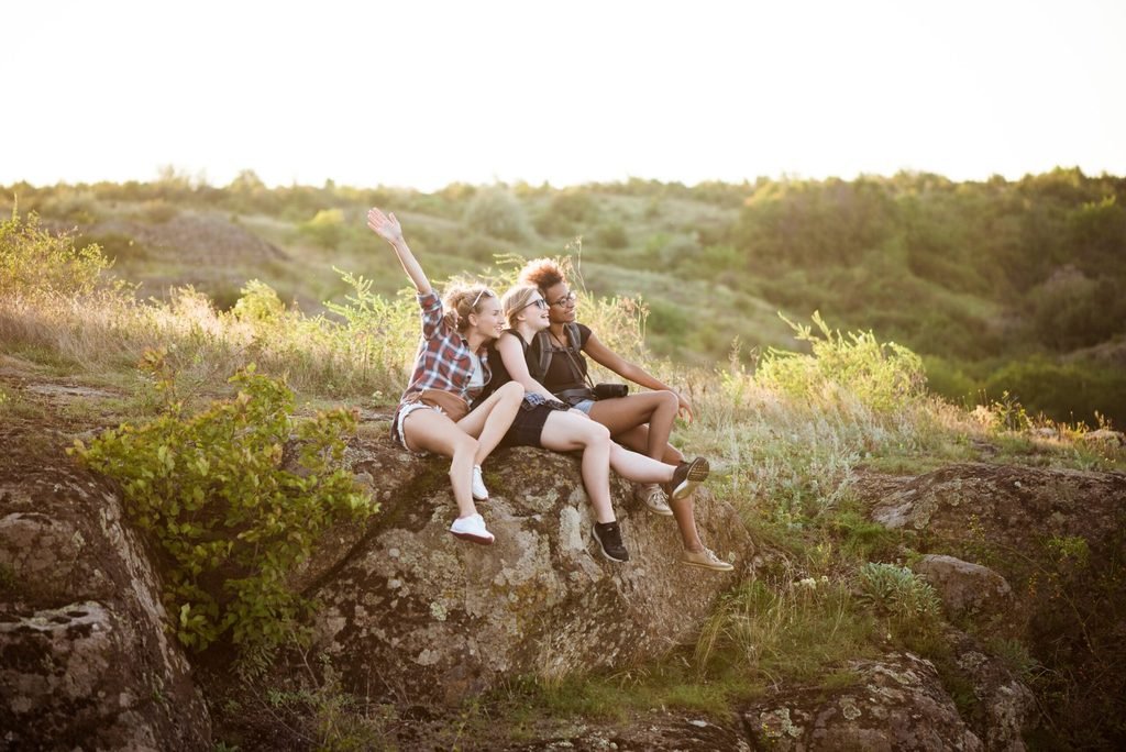 chicas-sonriendo-sentados-en-roca-disfrutando-de-la-vista-en-el-canon-scaled